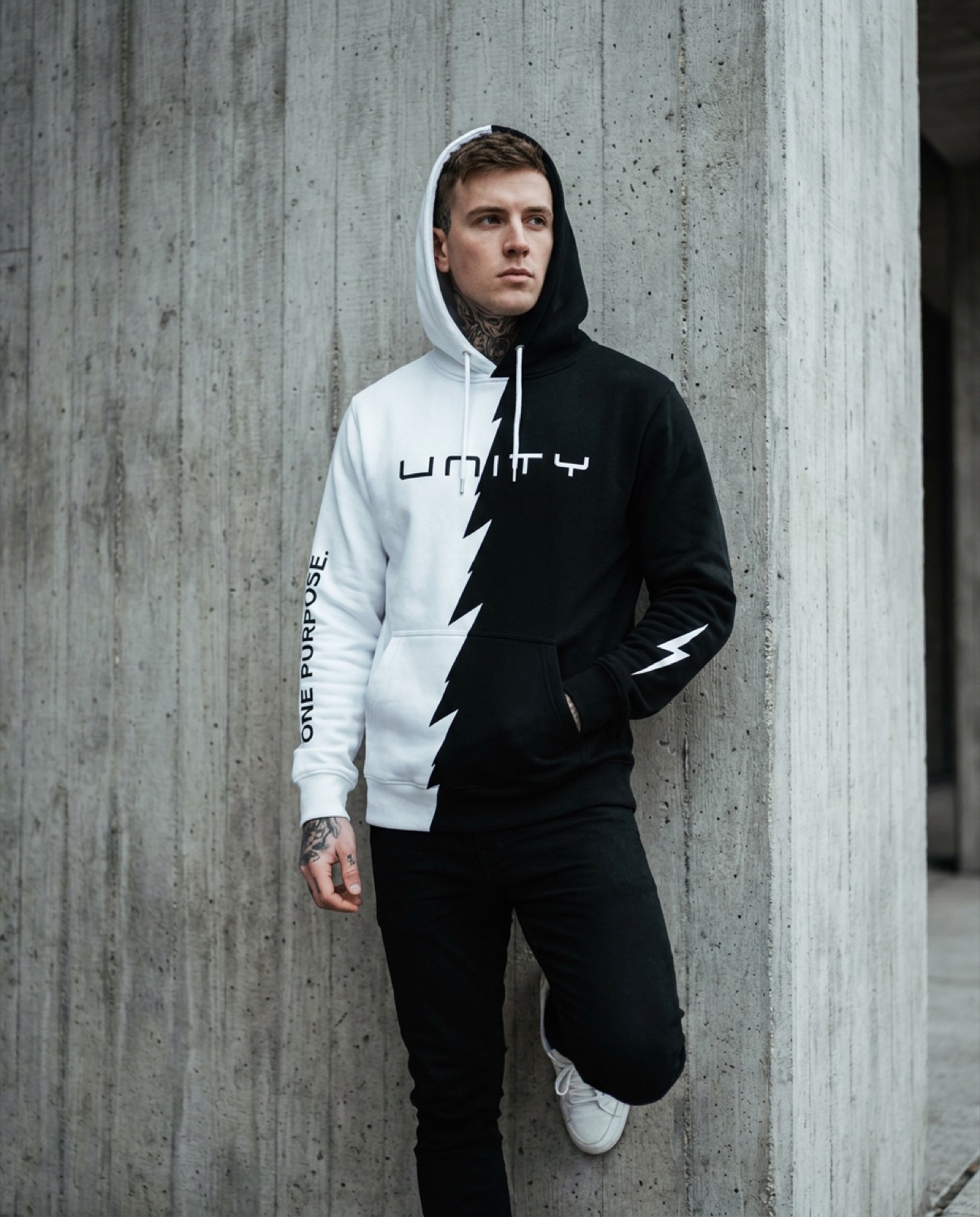 Model in UNITY split hoodie against a concrete wall